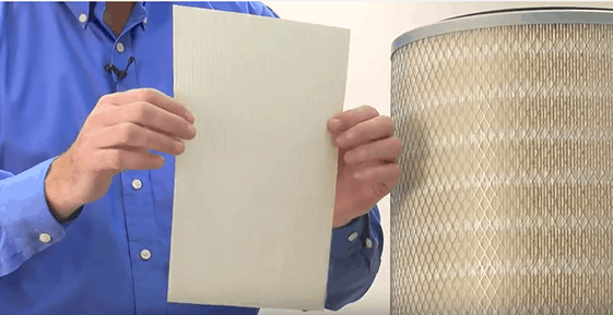 Hands holding dust collector filter media next to a cartridge filter