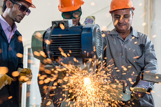 People working behind a welding machine with sparks
